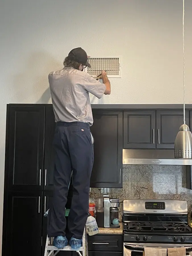 Technician inspecting an air vent during HVAC service in Eagan